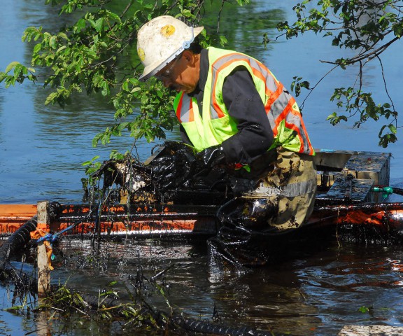 A worker lifts bitumen-covered debris from the Kalamazoo River