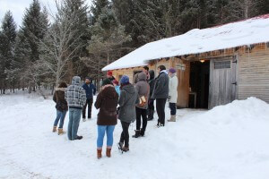 Nathan Scott answers questions from UNB students and CCNB staff Olivia, Karyn and Pascale in front of the Sap House at Dumfries Maples.