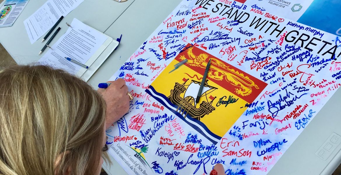 FridayForFuture14 Students sign a poster calling for climate action in New Brunswick during a #FridaysforFuture rally at the New Brunswick Legislature in March 2019.