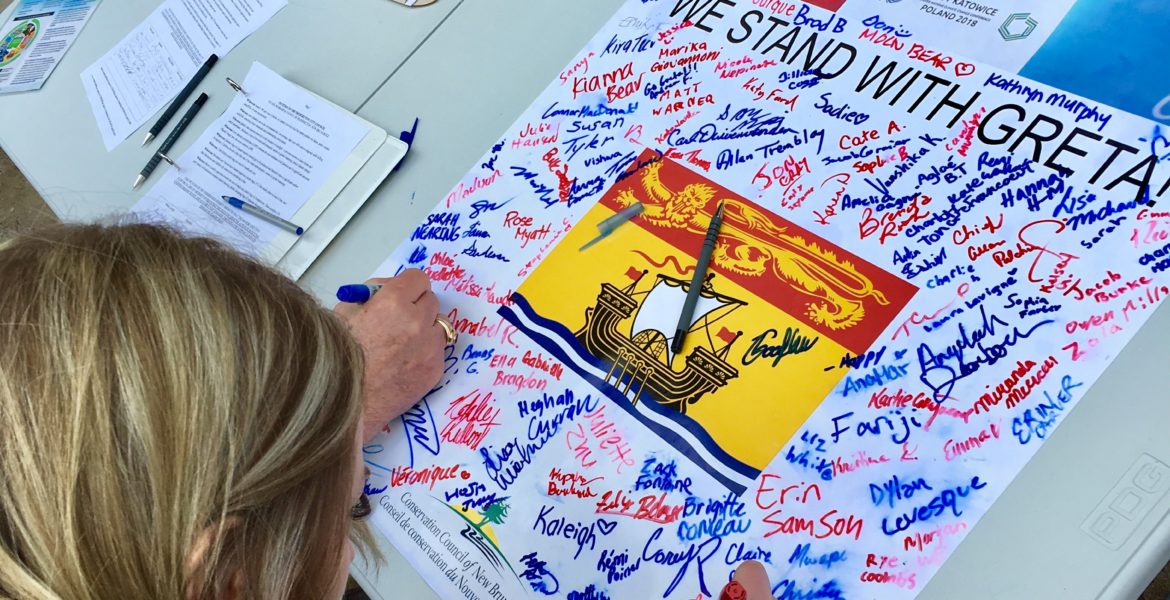 Students sign a poster calling for climate action in New Brunswick during a #FridaysforFuture rally at the New Brunswick Legislature in March 2019.