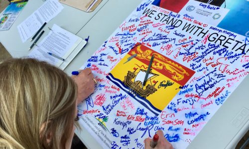 FridayForFuture14 Students sign a poster calling for climate action in New Brunswick during a #FridaysforFuture rally at the New Brunswick Legislature in March 2019.