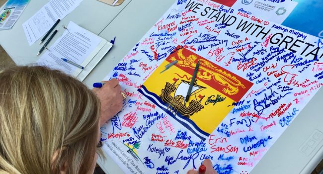 Students sign a poster calling for climate action in New Brunswick during a #FridaysforFuture rally at the New Brunswick Legislature in March 2019.
